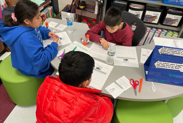 Three elementary-aged students - some of whom are English Learners or students in special education - sit at a table and work as a team as part of the Model of Instruction for Deeper Learning.